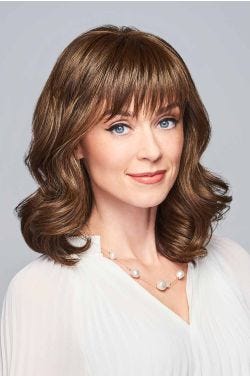 Woman in a shoulder length golden brown curly wig with textured bangs
