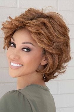 Woman in a textured light brown short bob wig with amply layering, longer hair at the nape, and textured fringe bangs