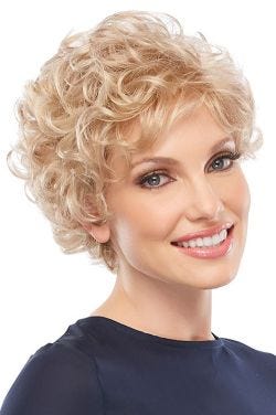 Woman in petite short curly blonde wig with bangs and layers for an older woman