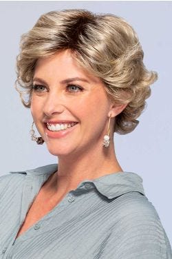 Woman in short curly blonde wig with bangs and layers for an older woman