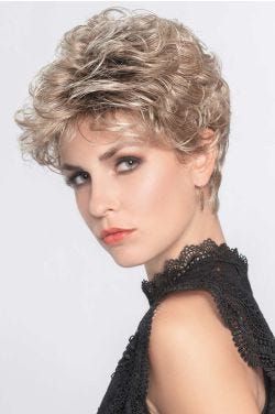 Woman in a curly light blonde pixie wig with longer layers on top