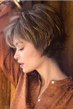 Woman in a long light brown pixie wig with fringe bangs and shorter, spiky layering in back