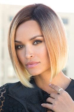 Woman in a past the chin light blonde angled blunt bob wig with dark roots