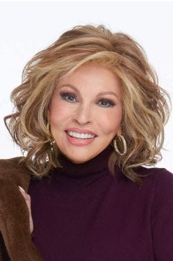 Raquel Welch in a shoulder length ginger blonde curly wig with wispy bangs