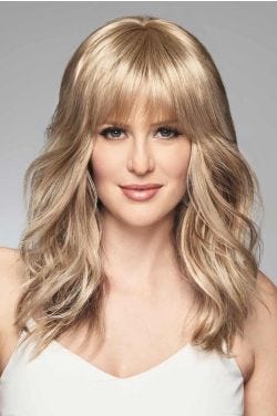 Woman in a long curly light blonde hair topper with fringe bangs