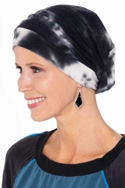 Woman in black and white tie dyed turban snood for cancer patients