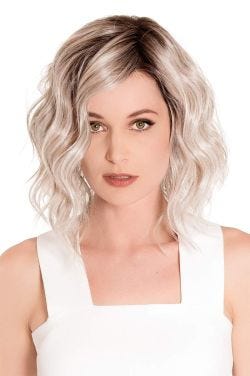Woman in a chin length platinum blonde wavy wig with dark roots