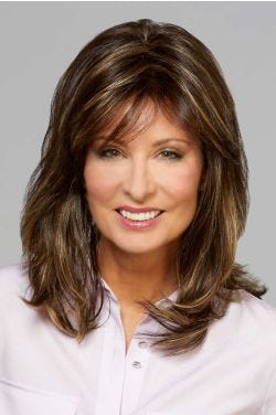 Woman in a past the shoulders dark brown wig with long layers and wispy bangs
