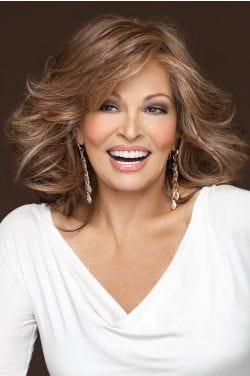 Raquel Welch in a just past the shoulders medium auburn long layered wig with long side swept bangs