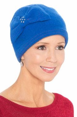 Woman in cute blue wool winter beanie hat with bow and rhinestone decoration