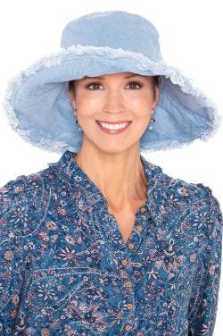 Woman in spring and summer extra wide brimmed denim floppy hat with wired brim and distressed edges for cancer patients