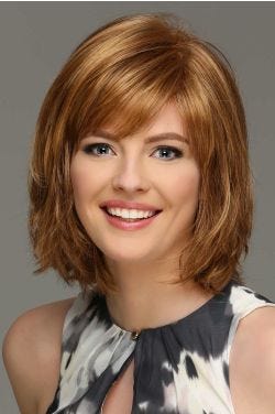 Woman in a chin length light auburn wig with side bangs