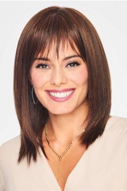 Woman in a past the shoulders straight medium brown wig with bangs
