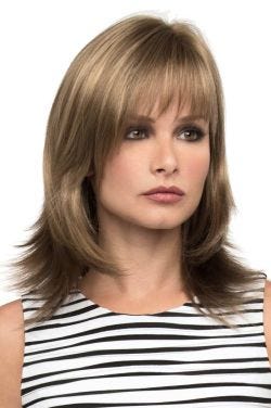 Woman in a shoulder length dark ash blonde wig with feathered layers and arched bangs