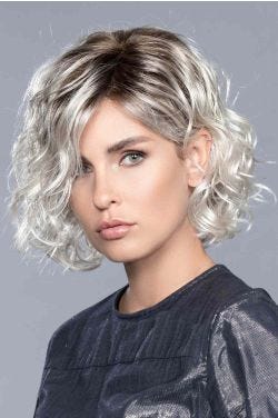 Woman in a chin length curly light grey lace front wig with dark roots