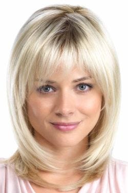 Woman in a past the shoulders platinum blonde layered wig with arched bangs