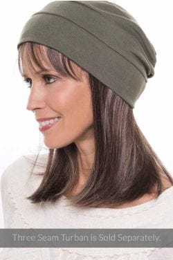 Woman in a long straight halo wig with bangs under an olive snood hat