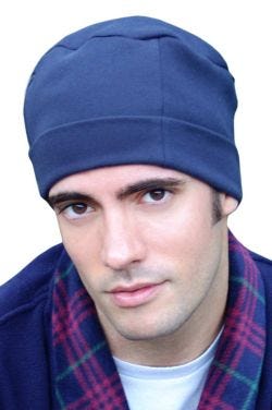 Man in soft navy organic cotton sleeping cap or night cap with adjustable cuff for balding, hair loss or chemo