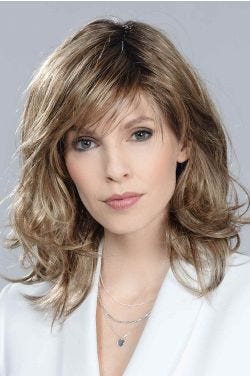 Woman in a shoulder length wavy layered light blonde wig with side bangs