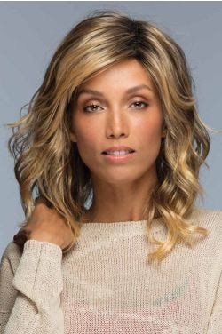Woman in a past the shoulders curly light brown wig with side bangs
