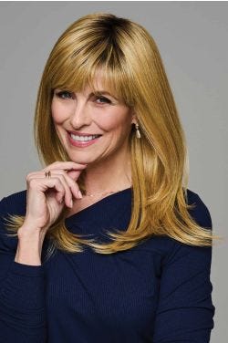 Woman wearing long layered blonde wig with side-swept bangs and smooth, shoulder-length ends