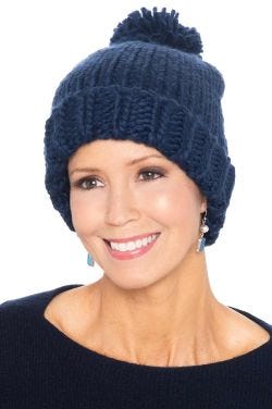 Woman in cute chunky blue cuffed knitted winter beanie hat with pom pom on top