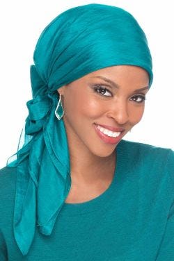 Woman in solid silk teal head scarf for women tied on her head into a bow