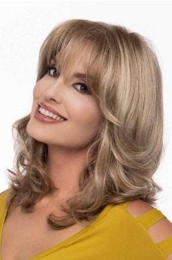 Woman in a past the shoulder curly dark brown wig with arched bangs