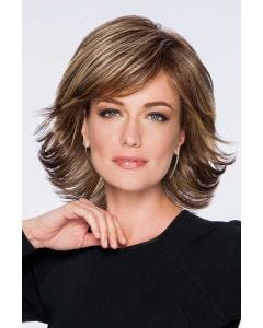 Woman in a shoulder length light brown wig with feathered layers and side bangs