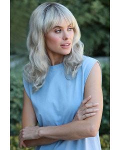Woman in a past the shoulders wavy medium brown wig with fringe bangs