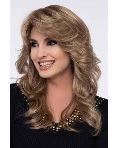 Woman in a past the shoulder curly light brown wig with feathered bangs