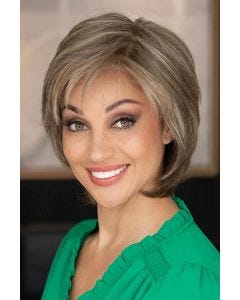 Woman in a shoulder length short light brown wig with long layers and side bangs