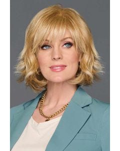 Woman in a past chin length gold blonde wavy layered wig with choppy bangs