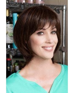 Woman in a shoulder length dark brown wig with long feathered layers and side bangs