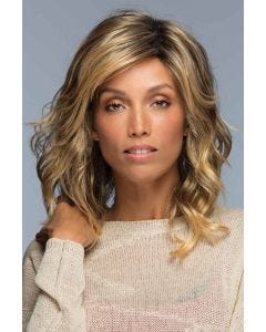 Woman in a past the shoulders curly light brown wig with side bangs