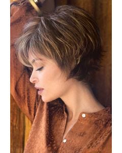 Woman in a long light brown pixie wig with fringe bangs and shorter, spiky layering in back