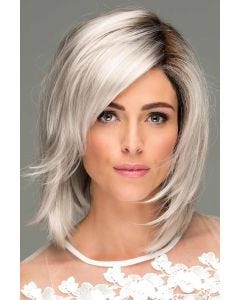 Woman in a shoulder length platinum blonde choppy layered wig with side bangs