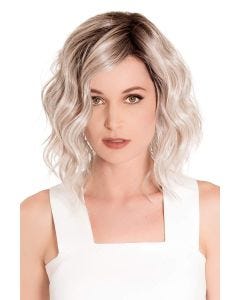 Woman in a chin length platinum blonde wavy wig with dark roots