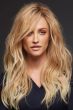 Woman in long, wavy strawberry blonde wig with with long side-swept bangs framing the face