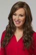 Woman in an extra long medium brown curly lace front wig