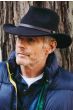Older man outdoors in black brimmed Australian outback hat with brown leather band