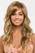 Woman in an extra long wavy light brown wig with side bangs