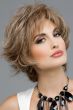 Woman in a textured light brown short bob wig with amply layering, longer hair at the nape, and textured fringe bangs