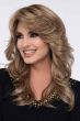 Woman in a past the shoulder curly light brown wig with feathered bangs