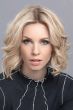 Woman in a chin length curly light blonde human hair/synthetic blend wig
