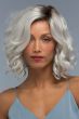 Woman in a shoulder length curly silver lace front wig with dark roots