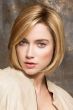 Woman in a chin length blunt reddish blonde bob wig with side bangs