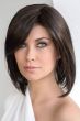 Woman in a shoulder length dark brown wig with long layers and side bangs