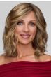 Woman in a past the shoulders light ash blonde wig with defined curls and dark roots