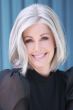 Woman in a shoulder length light blonde lace front bob wig with curled under ends and dark roots